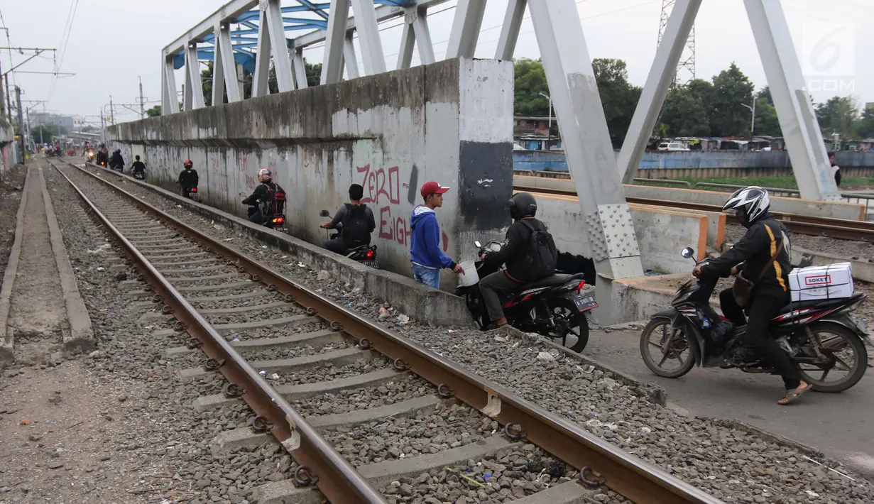 Suasana saat sejumlah pengendara melintas di samping rel kereta yang berada di kawasan Banjir Kanal Barat, Jakarta, Selasa (20/3). Mereka beralasan hal itu dilakukan demi mempersingkat waktu. (Liputan6.com/Arya Manggala)
