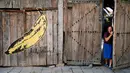 Seorang wanita keluar dari rumah yang dindingnya berhias lukisan mural bergambar pisang karya Andy Warhol di desa Staro Zhelezare di Bulgaria, 4 Agustus 2018. Para seniman mewarnai desa ini dengan mural outdoor besar yang berwarna. (AFP/Dimitar DILKOFF)