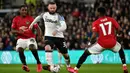 Pemain Derby County Wayne Rooney (tengah) mencoba melewati pemain Manchester United Odion Ighalo (kiri) dan Fred pada pertandingan putaran kelima Piala FA di Pride Park, Derby, Inggris, Kamis (5/3/2020). Manchester United menang dengan skor 3-0. (AP Photo/Rui Vieira)