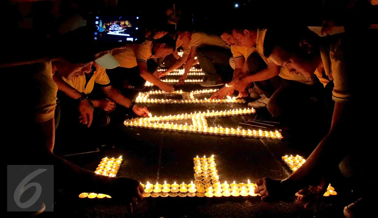 Puluhan karyawan Artha Graha Peduli menyalakan lilin saat menggelar Earth Hours di kawasan SCBD Jakarta, Sabtu (25/3). Kegiatan ini mendukung kampanye perubahan iklim dan pencegahan pemanasan global dengan pemadaman listrik. (Liputan6.com/Fery Pradolo)