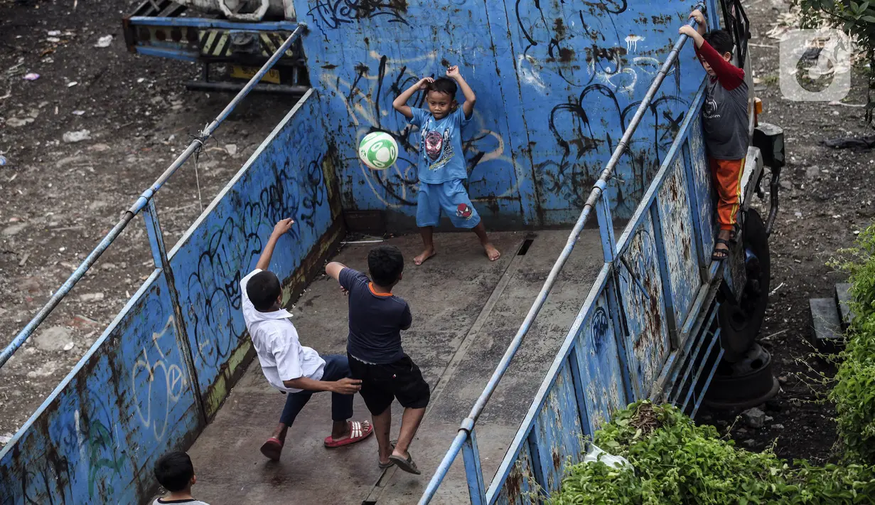 Sejumlah anak bermain sepak bola dalam bak truk di kawasan Cengkareng, Jakarta, Rabu (23/2/2022). Minimnya lahan bermain di kawasan tersebut membuat anak-anak memanfaatkan tempat yang bukan semestinya untuk bermain bola. (Liputan6.com/Johan Tallo)