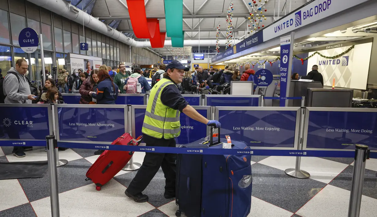 Seorang karyawan United Airlines mendorong bagasi di Terminal 1 menjelang Liburan Natal di Bandara Internasional O'Hare di Chicago (22/12/2022). Peramal cuaca AS memperingatkan cuaca yang mengancam jiwa karena badai musim dingin mengancam akan mendatangkan malapetaka pada rencana perjalanan liburan bagi jutaan orang Amerika. (AFP/Kamil Krzaczynski)