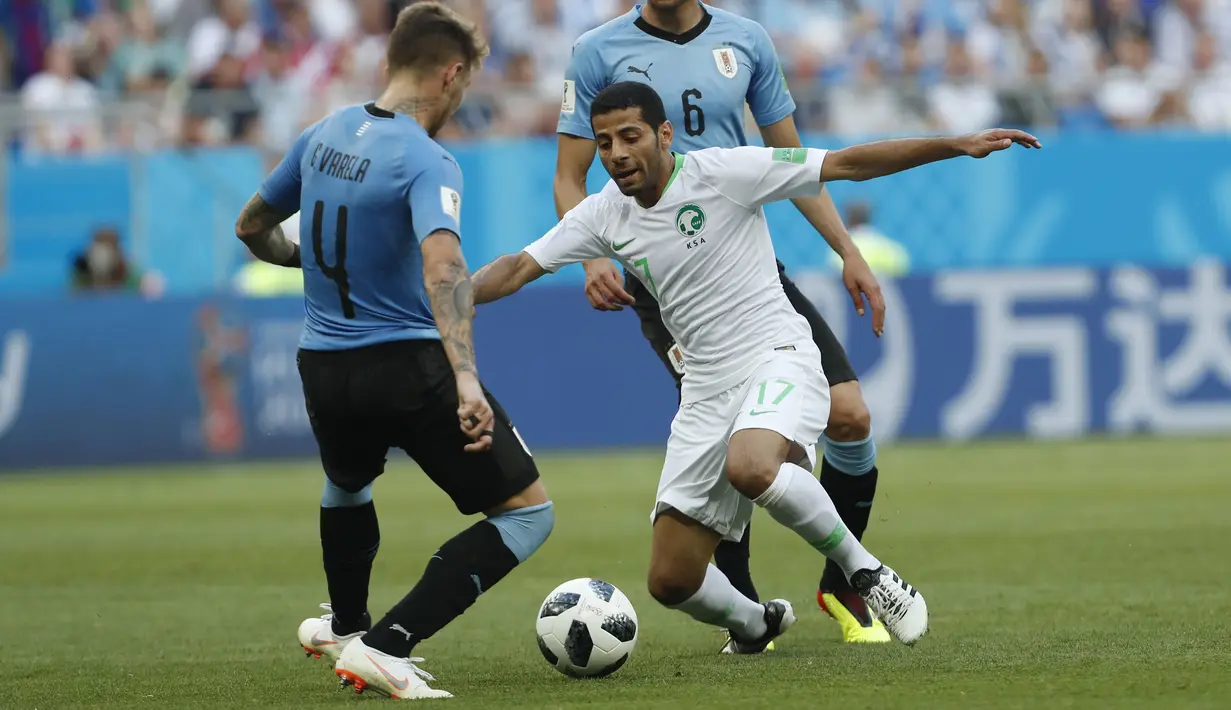 Pemain Arab Saudi, Taiseer Aljassam (tengah) berusaha melewati adangan pemain Uruguay, Guillermo Varela pada laga grup A Piala Dunia 2018 di Rostov Arena, Rostov-on-Don, Rusia, (20/6/2018). Uruguay menang 1-0. (AP/Darko Vojinovic)