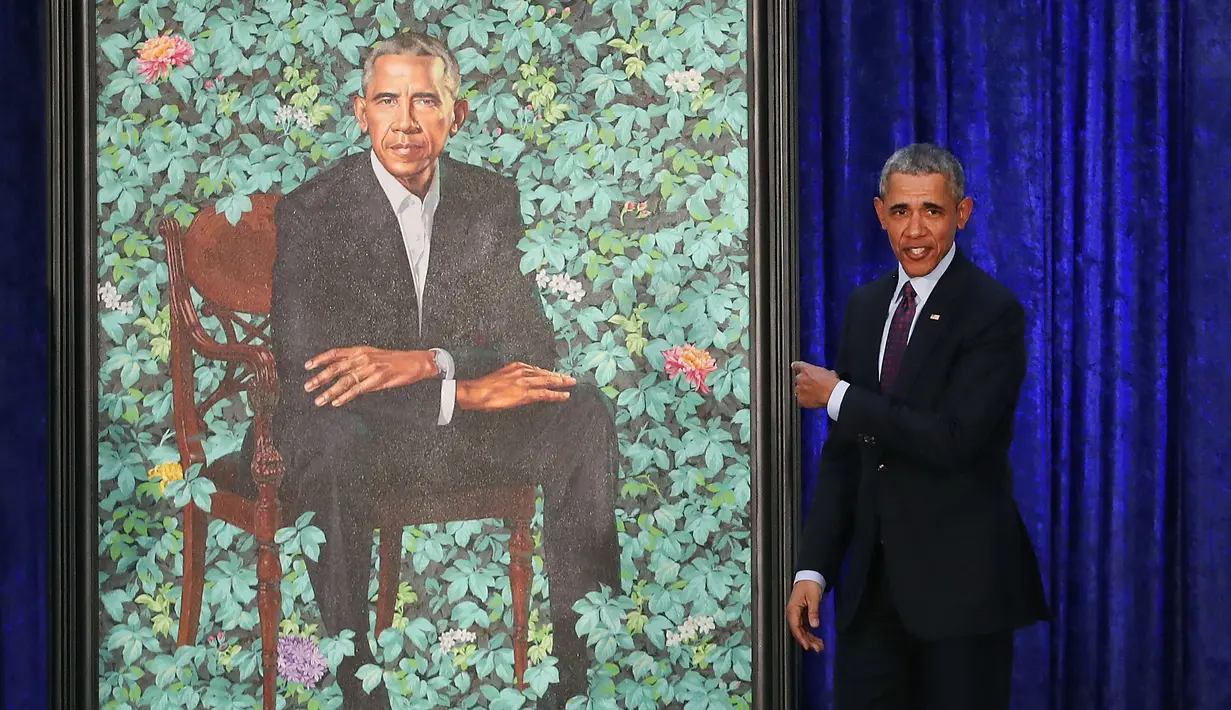 Presiden AS ke-44 Barack Obama menujuk lukisan dirinya saat upacara peresmian di Galeri Potret Nasional Smithsonian, Washington DC (12/2). Potret Presiden Obama ini dibuat oleh Kehinde Wiley. (Mark Wilson/Getty Images/AFP)