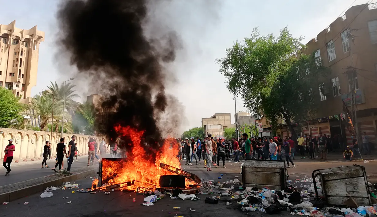 Pengunjuk rasa antipemerintah membakar sejumlah benda dan memblokir jalan saat menggelar protes di Baghdad, Irak, Rabu (2/10/2019). Ribuan demonstran berhadapan dengan tembakan dan gas air mata dalam unjuk rasa yang terjadi di sejumlah kota di Irak. (AP Photo/Hadi Mizban)