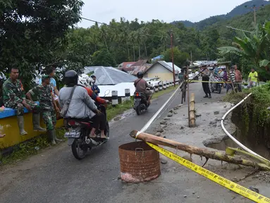 Kendaraan melintas dekat lokasi jalan longsor di Desa Bondawuna, Kabupaten Bone Bolango, Gorontalo, Selasa (30/4/2019). Hujan yang mengguyur wilayah Kabupaten Bone Bolango mengakibatkan empat desa di Kecamatan Suwawa Selatan, dan Bulango Timur Bone Bolango banjir. (Liputan6.com/Arfandi Ibrahim)