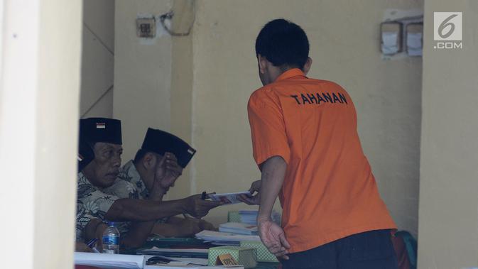 Tahanan mengambil surat suara saat akan mencoblos di TPS 15 Rutan Polda Metro Jaya, Jakarta, Rabu (17/4). Anggota kepolisian yang bertugas dilarang untuk memasuki lokasi TPS yang telah disediakan. (Liputan6.com/Herman Zakharia)