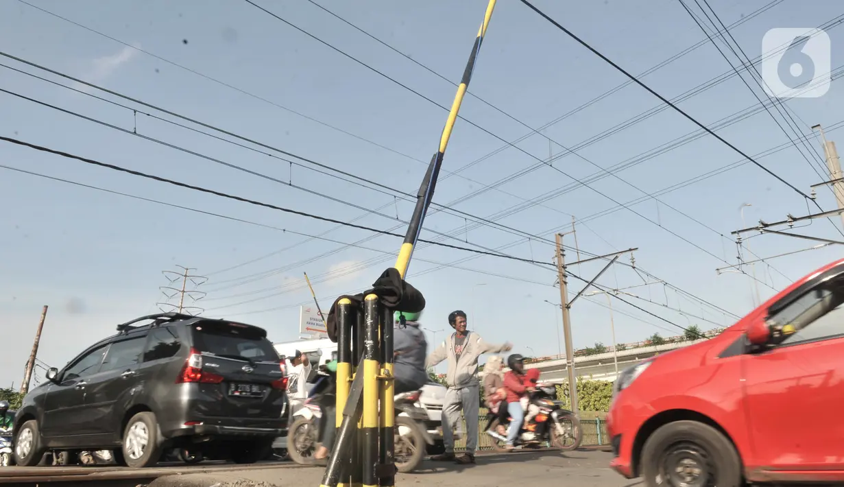 Warga mengatur lalu di perlintasan kereta api di Jalan Duri Kosambi Raya, Jakarta, Rabu (15/1/2020).  Warga setempat membangun palang secara swadaya dan mengatur lalu lintas akibat perlintasan kereta dekat  Stasiun Rawa Buaya tersebut belum dipasang palang pintu otomatis. (merdeka.com/Iqbal Nugroho)