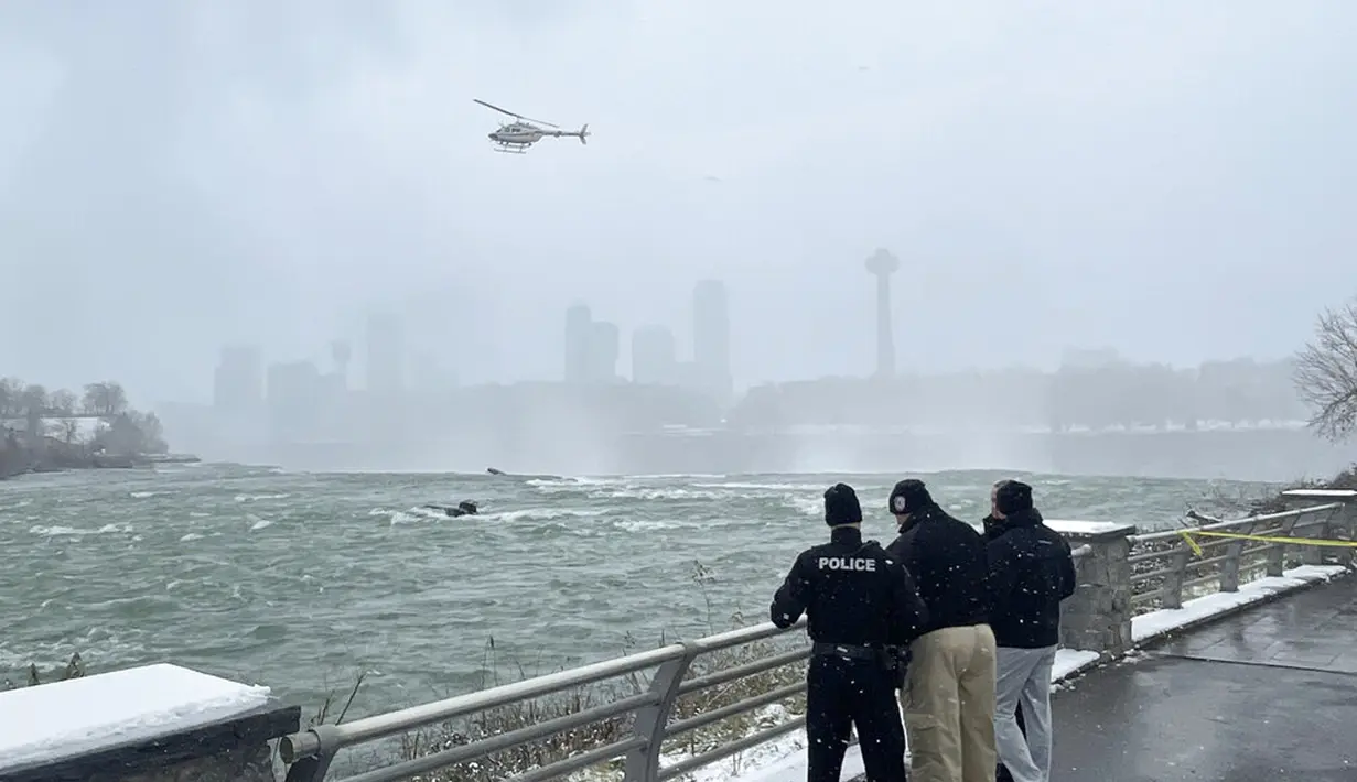 Pihak berwenang memantau sebuah mobil yang terjebak dalam arus deras di tepi Air Terjun Niagara, New York, AS, 8 Desember 2021. Mobil terjebak dalam arus deras sekitar 50 meter dari tepi Air Terjun Niagara. (Larry Kensinger/NC News Service via AP)