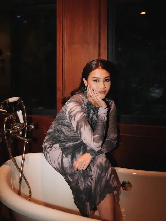 Di sini, Aaliyah Massaid tampil berpose di bathtub dengan tie dye dress berwarna hitam-putih. Gaya elegan Aaliyah disempurnakan dengan makeup bold dan rambut panjang ditata ikal dibiarkan tergerai. [Foto: Instagram/aaliyah.massaid]