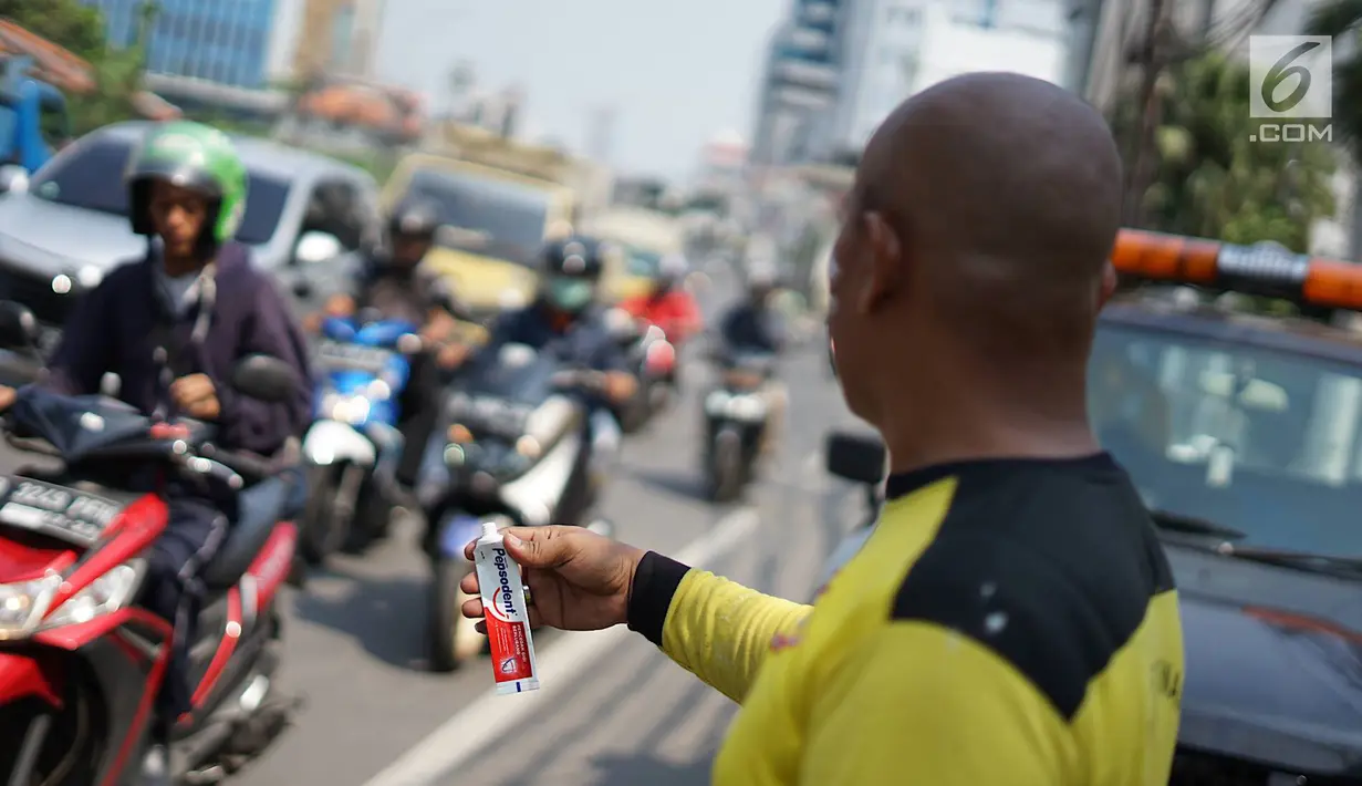 Petugas Sudin Bina Marga Jakarta Barat membagikan masker dan pasta gigi kepada pengendara motor di Jalan KS Tubun, Petamburan, Kamis (23/5/2019). Sisa gas air mata untuk membubarkan massa dalam kericuhan aksi 22 Mei masih terasa dan mengganggu aktvitas pengguna jalan (Liputan6.com/Immanuel Antonius)