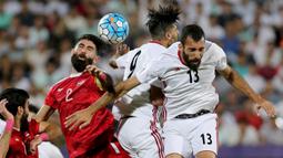 Bek Suriah, Moualad al-Ajjan, duel udara dengan pemain Iran pada laga kualifikasi Piala Dunia 2018 di Stadion Azadi, Taheran, Selasa (5/9/2017). Finis urutan tiga grup A, Suriah lolos ke babak playoff untuk menantang Australia. (AFP/Atta Kenare)