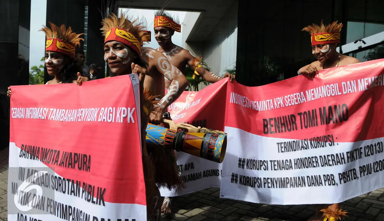 Sejumlah pemuda Papua mengenakan pakaian adat membentangkan spanduk saat menggelar unjuk rasa di depan Gedung KPK, Jakarta, Senin (19/12). (Liputan6.com/Helmi Affandi)