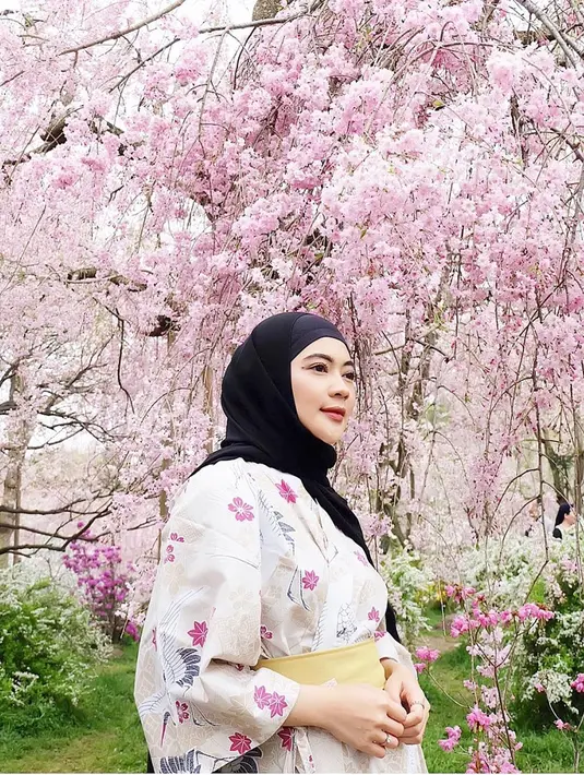Saat berkunjung ke Jepang, tidak lengkap rasanya menggunakan baju tradisionalnya yaitu Kimono. Seperti yang dipakai oleh IDP ini. Meski dibalut dengan hijab hitam, dirinya memesona dengan kimono berwarna pink dengan latar belakang bunga sakura yang indah. (Liputan6.com/IG/@idp91)