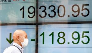 Seorang pria berjalan melewati indikator saham elektronik sebuah perusahaan sekuritas di Tokyo (29/8). Rudal tersebut menuju wilayah Tohoku dekat negara Jepang. (AP Photo/Shizuo Kambayashi)