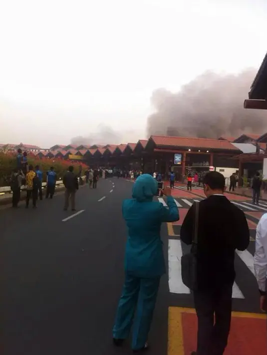 Tampak seorang mengabadikan gambar kebakaran di Terminal 2E di Bandara Soekarno Hatta, Jakarta, Minggu (5/7/2015). Hingga kini penyebab terjadinya kebakaran tersebut belum diketahui dan masih dalam penyelidikan. (Twitter@baabullah)