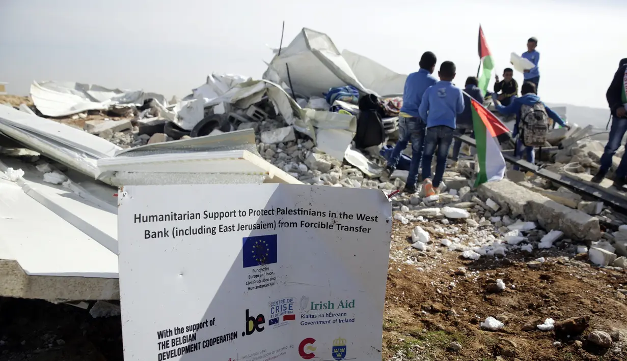 Suasana saat anak-anak bermain di antara puing-puing sekolah mereka yang hancur di Desa Abu Nuwar, Tepi Barat, Palestina, Minggu (4/2). Sekolah tersebut melayani hampir 30 siswa kelas tiga dan empat. (AP Photo/Mahmoud Illean)