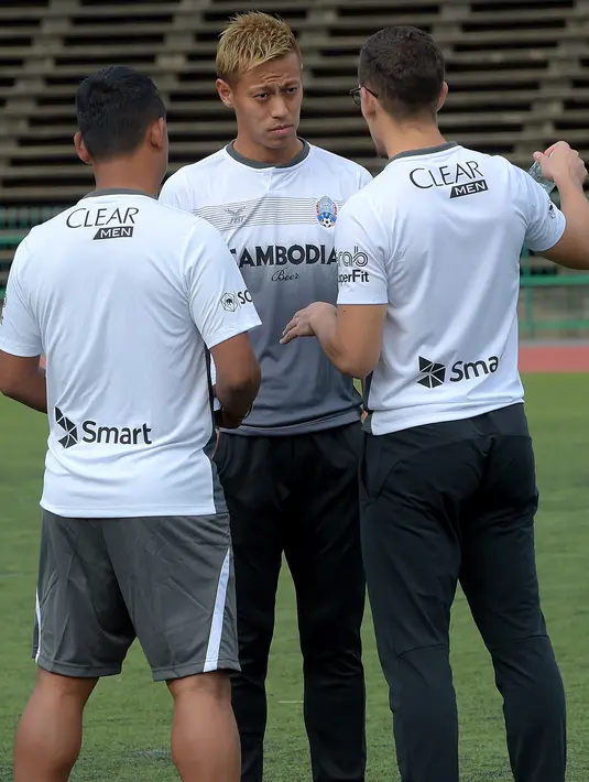 Keisuke Honda (tengah) berbincang dengan pejabat timnas Kamboja selama sesi pelatihan di Stadion Nasional Olimpiade di Phnom Penh, (4/9). Federasi Sepak Bola Kamboja (FFC) mengontrak Honda menjadi pelatih berdurasi dua tahun. (AFP Photo/Tang Chhin Sothy)