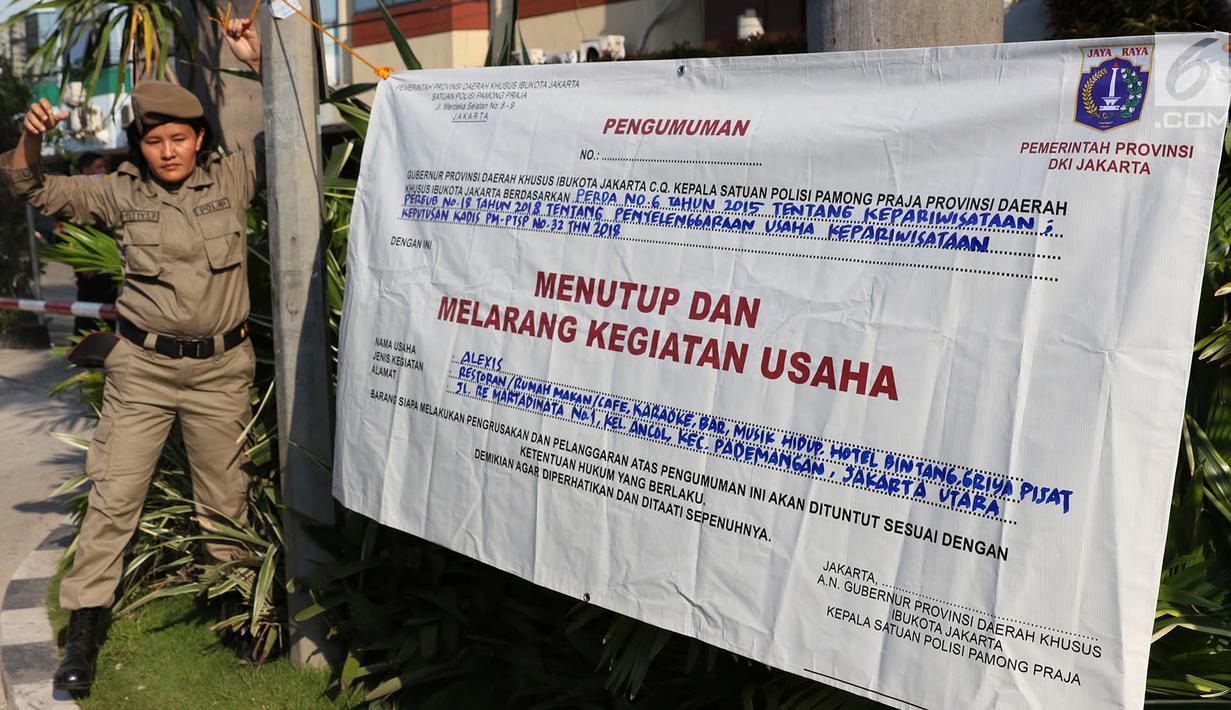 Personel Satpol PP wanita memasang spanduk penyegelan untuk menutup Hotel Alexis, Jakarta, Kamis (29/3). Ibu-ibu personel Satpol PP ini bertugas untuk memastikan tidak ada kegiatan usaha apapun di Hotel Alexis. (Liputan6.com/Immanuel Antonius)