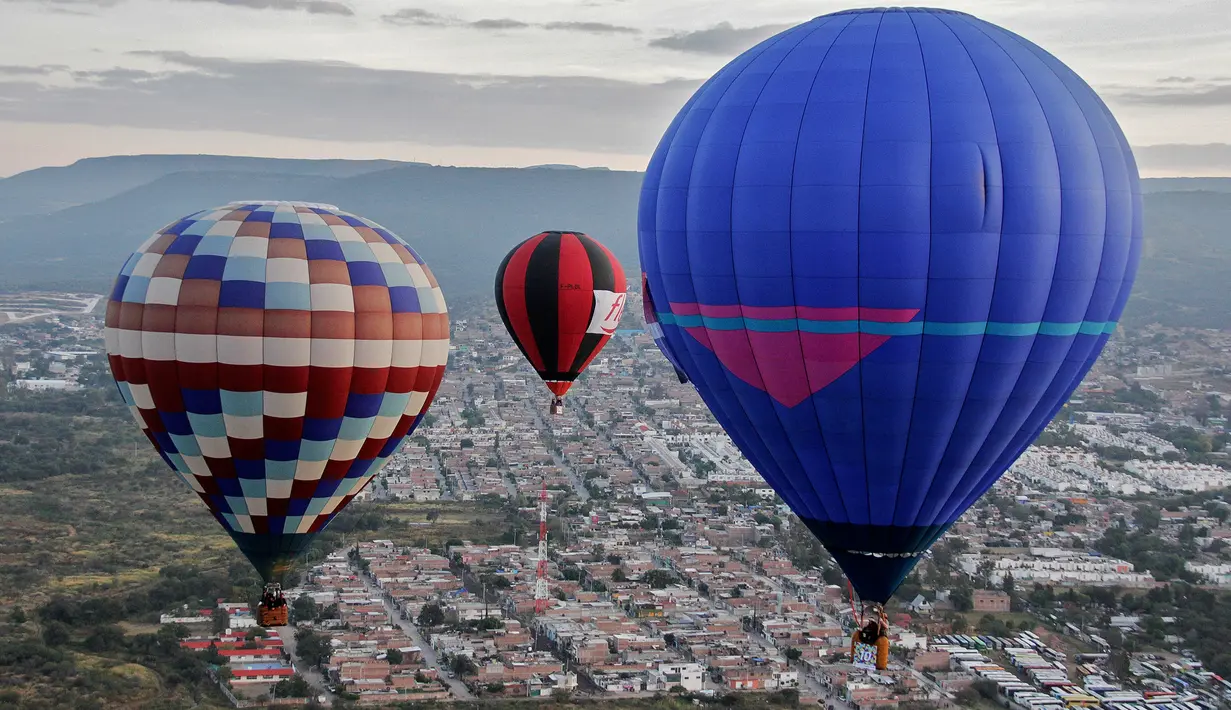Sejumlah peserta mengikuti Festival Balon Udara Internasional XVIII di Taman Metropolitan, Leon, negara bagian Guanajuato, Meksiko pada 16 November 2019. Tak hanya balon udara biasa, banyak yang memiliki bentuk, serta warna unik menyemarakkan langit Kota Leon. (MARIO ARMAS / AFP)
