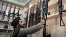 Seorang pedagang senjata Hakimullah Afridi memajang senapan otomatis buatan lokal di tokonya, Darra Adamkhel, Pakistan, 14 Desember 2022. Pasar gelap senjata di Kota Darra Adamkhel dipenuhi dengan senapan Amerika palsu, replika revolver, dan AK-47 palsu. (Abdul MAJEED/AFP)