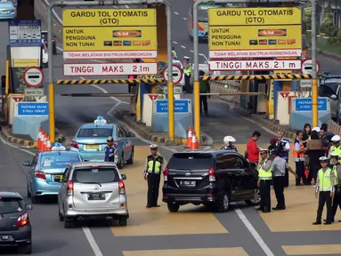 Petugas mengarahkan kendaraan berplat genap berputar balik di Gerbang Tol Bekasi Barat 1, Bekasi, Jawa Barat, Selasa (13/3). Hari kedua penerapan ganjil genap, masih banyak kendaraan berputar balik di gerbang tol tersebut. (Liputan6.com/Arya Manggala)