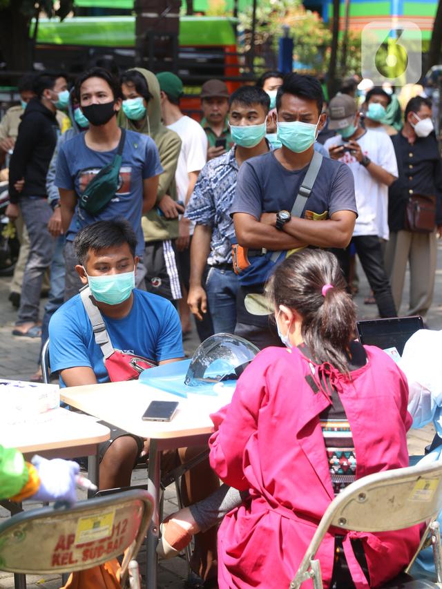 Warga antre menunggu untuk menjalani tes deteksi COVID-19 dengan metode GeNose C19 usai terjaring razia penggunaan masker di Kelurahan Sudimara Barat, Kota Tangerang, Kamis (27/5/2021). Tes tersebut untuk menekan penyebaran corona di wilayah tersebut. (Liputan6.com/Angga Yuniar)