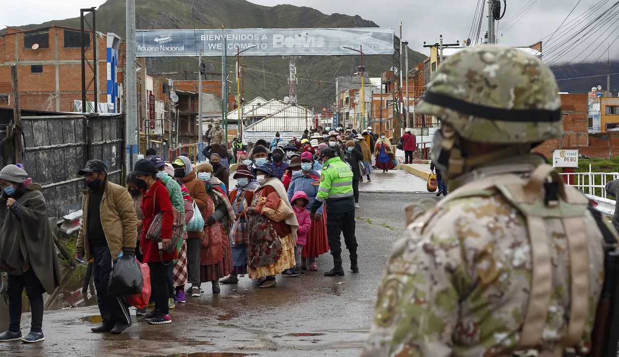 Seorang tentara memeriksa lalu lintas pejalan kaki di perbatasan Peru dengan Bolivia di desa Desaguadero, Peru, pada 18 Februari 2022. Pemerintah Peru membuka kembali perbatasan dengan Bolivia dan Ekuador setelah ditutup hampir dua tahun karena pandemi Covid-19. (Carlos MAMANI/AFP)