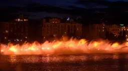 Petugas pemadam kebakaran menyemprotkan air ke Sungai Vltava berhias cahaya kuning untuk menandai HUT ke-100 Ceko di Praha, Sabtu (2/6). (Michal Cizek/AFP)