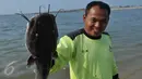 Petugas memperlihatkan ikan yang mati di sepanjang reklamasi pantai Ancol, Jakarta (30/11/2015). Ribuan ikan yang mati dan terdampar di pantai ini diduga akibat tercemar limbah industri. (Liputan6.com/Gempur M Surya)
