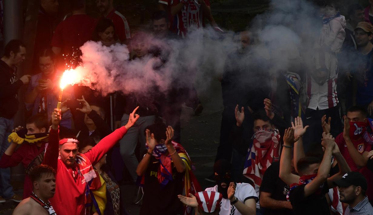 Warga Madrid menyalakan flare saat menyambut konvoi Atletico Madrid merayakan gelar Liga Europa di Madrid, Jumat (18/5/2018). Kota Madrid menjadi merah saat perayaan gelar juara Atletico. (AFP/Javier Soriano)