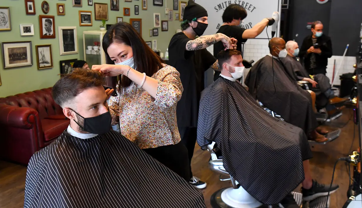 Para pria memotong rambut di barber shop di Melbourne, Australia, Senin (19/10/2020). Warga Kota Melbourne, pada Senin (19/10), akhirnya bisa bernafas lega saat sejumlah pembatasan dilonggarkan setelah menjalani lockdown tahap keempat yang ketat selama sekitar 100 hari. (William WEST/AFP)