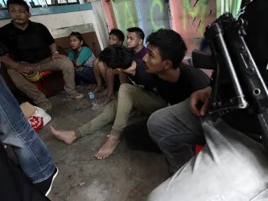 Sejumlah tersangka tertunduk lesu usai polisi menggerebek peredaran narkoba di kawasan Kampung Ambon, Cengkareng, Jakarta Barat, Rabu (24/1). Dalam penggerebekan tersebut polisi menangkap enam tersangka. (Liputan6.com/Arya Manggala)