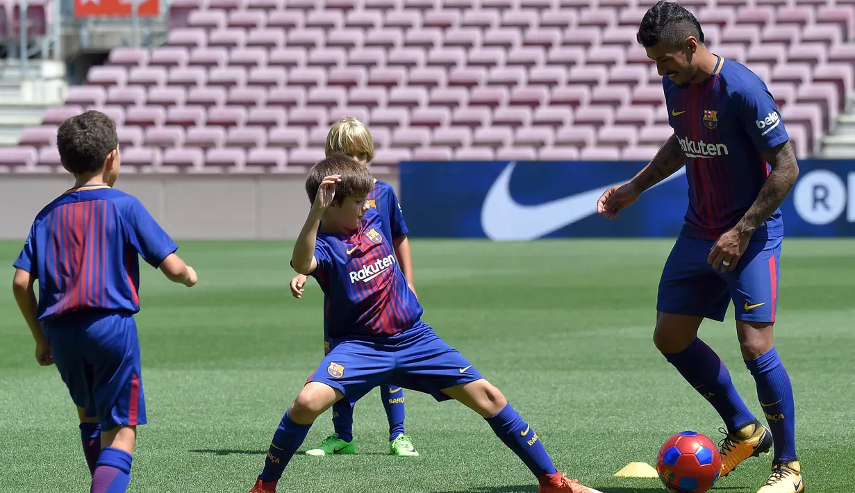 Gelandang baru Barcelona, Paulinho bermain bola dengan anak-anak saat perkenalan dirinya di Stadion Nou Camp, Barcelona, (17/8). Paulinho meneken kontrak empat musim di Camp Nou. (AFP Photo/Lluis Gene)
