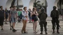 Wisatawan berbincang dengan tentara saat mereka berpatroli di lingkungan Lapa di Rio de Janeiro, Brasil, (30/7). Ribuan tentara mulai berpatroli di Rio de Janeiro di tengah lonjakan kekerasan di kota terbesar kedua di Brasil. (AP Photo / Leo Correa)
