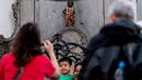 Wisatawan berfoto dekat patung 'Manneken Pis' dalam balutan baju bermotif bunga di ibu kota Belgia, Brussels, Senin (12/8/2019). Patung anak laki-laki yang sedang buang air kecil ini menjadi salah satu daya tarik uta di kota cantik tersebut. (Photo by Kenzo TRIBOUILLARD / AFP)