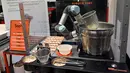 Robot koki bernama Sophie meracik semangkuk laksa saat demonstrasi memasak di Singapura pada 26 Juli 2019. Robot koki ini bisa merebus mie, menambahkan udang, dan menuangkan sup ke sebuah mangkuk. (Roslan RAHMAN / AFP)