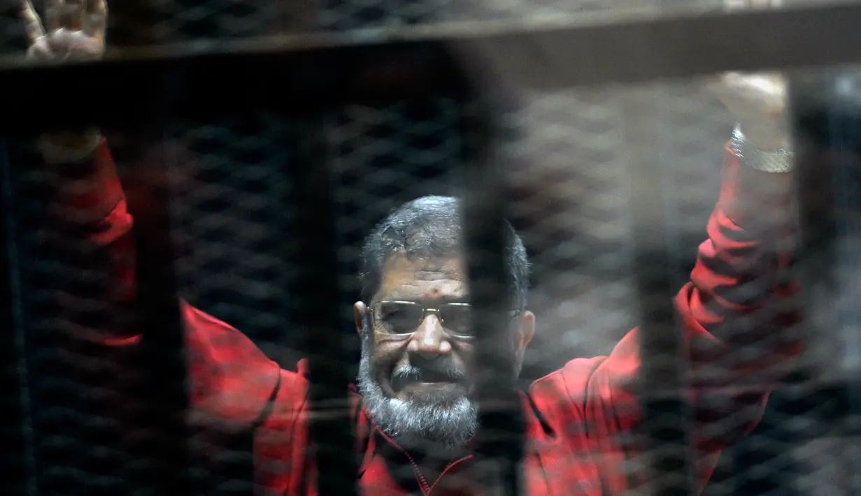 Mantan Presiden Mesir Mohammed Morsi mengenakan seragam merah yang menandakan dia telah dijatuhi hukuman mati saat menjalani sidang sementara di Akademi Kepolisian Nasional, Kairo, Mesir, 21 Juni 2015. Mohammed Morsi meninggal pada Senin 17 Juni 2019 waktu setempat. (AP Photo/Ahmed Omar, File)