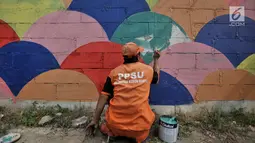 Petugas PPSU mengecat saat pembuatan mural pada tembok yang berada di pinggir Jalan Landasan Pacu, Jakarta, Rabu (11/7). Pengecatan dan pembuatan mural ini dalam rangka mempercantik kawasan serta menyambut Asian Games 2018. (Merdeka.com/Iqbal S. Nugroho)