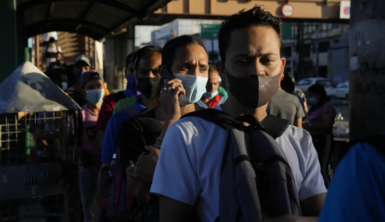 Komuter yang mengenakan masker menunggu kendaraan di halte bus di metro Manila, Filipina, Kamis (8/9/2022). Presiden Filipina Ferdinand Marcos Jr. telah menyetujui rekomendasi untuk mengakhiri wajib memakai masker di luar ruangan di seluruh negeri. (AP Photo/Aaron Favila)