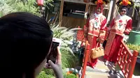 Pengunjung berfoto di jembatan merah Chinatown dengan kostum khas Tiongkok. Foto: (Huyugo Simbolon/Liputan6.com)