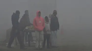 Penduduk Pakistan menunggu angkutan di tengah kabut asap tebal di Lahore (3/1). Tingkat kabut asap melonjak selama musim dingin di Pakistan selatan, ketika kualitas udara melampaui level aman Organisasi Kesehatan Dunia. (AFP Photo/Arif Ali)