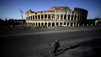Seorang pria membawa anjingnya jalan-jalan di depan Colosseum, Roma, Italia, 3 April 2020. Menurut Departemen Perlindungan Sipil Italia pada 6 April 2020, jumlah kasus virus corona COVID-19 di negara tersebut menjadi 132.547 infeksi, 16.523 meninggal, dan 22.837 sembuh. (Filippo MONTEFORTE/AFP)
