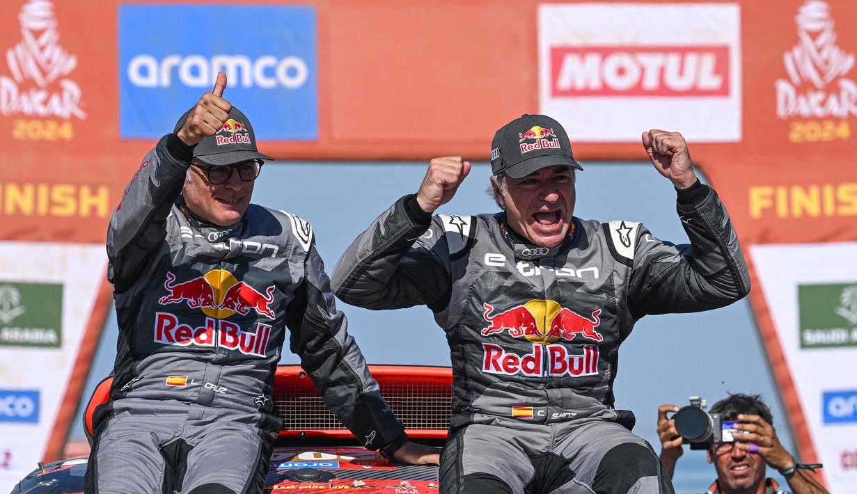 Pembalap Team Audi Sport, Carlos Sainz (kanan) dan co-driver, Lucas Cruzof merayakan kemenangan setelah menyelesaikan etape terakhir Reli Dakar 2024 di Yanbu, Arab Saudi, Jumat, 19 Januari 2024 waktu setempat. (AFP/Patrick Hertzog)