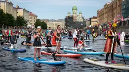 Sejumlah peserta mengenakan kostum mendayung papan Stand Up Paddle (SUP) di kanal Kryukov saat Surfing festival di St.Petersburg, Rusia (8/7). Olahraga ini tidak hanya dimainkan di laut saja, tetapi bisa disungai atau danau. (AP Photo / Dmitri Lovetsky)