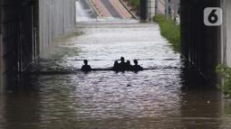 Warga melintasi banjir di terowongan Jalan Angkasa, Jakarta, Selasa (25/2/2020). Hujan yang mengguyur Jakarta sejak Senin (24/2) malam membuat sejumlah kali meluap dan menyebabkan banjir di terowongan tersebut. (Liputan6.com/Helmi Fithriansyah)