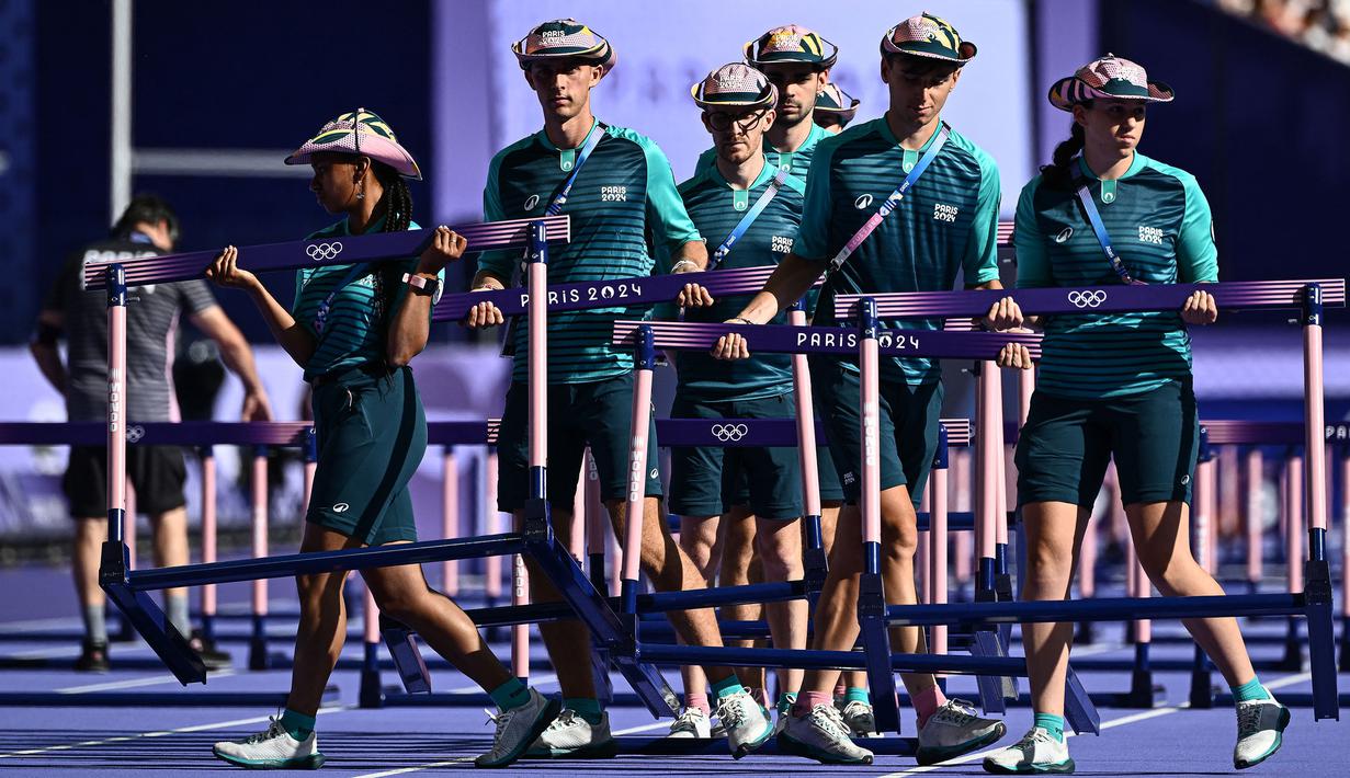 Sejumlah volunter sedang mempersiapkan lintasan cabang olahraga heptathlon 100m rintangan putri di Olimpiade Paris 2024 di Stade de France, Paris, Prancis pada 8 Agustus 2024. (AFP/Jewel Samad)