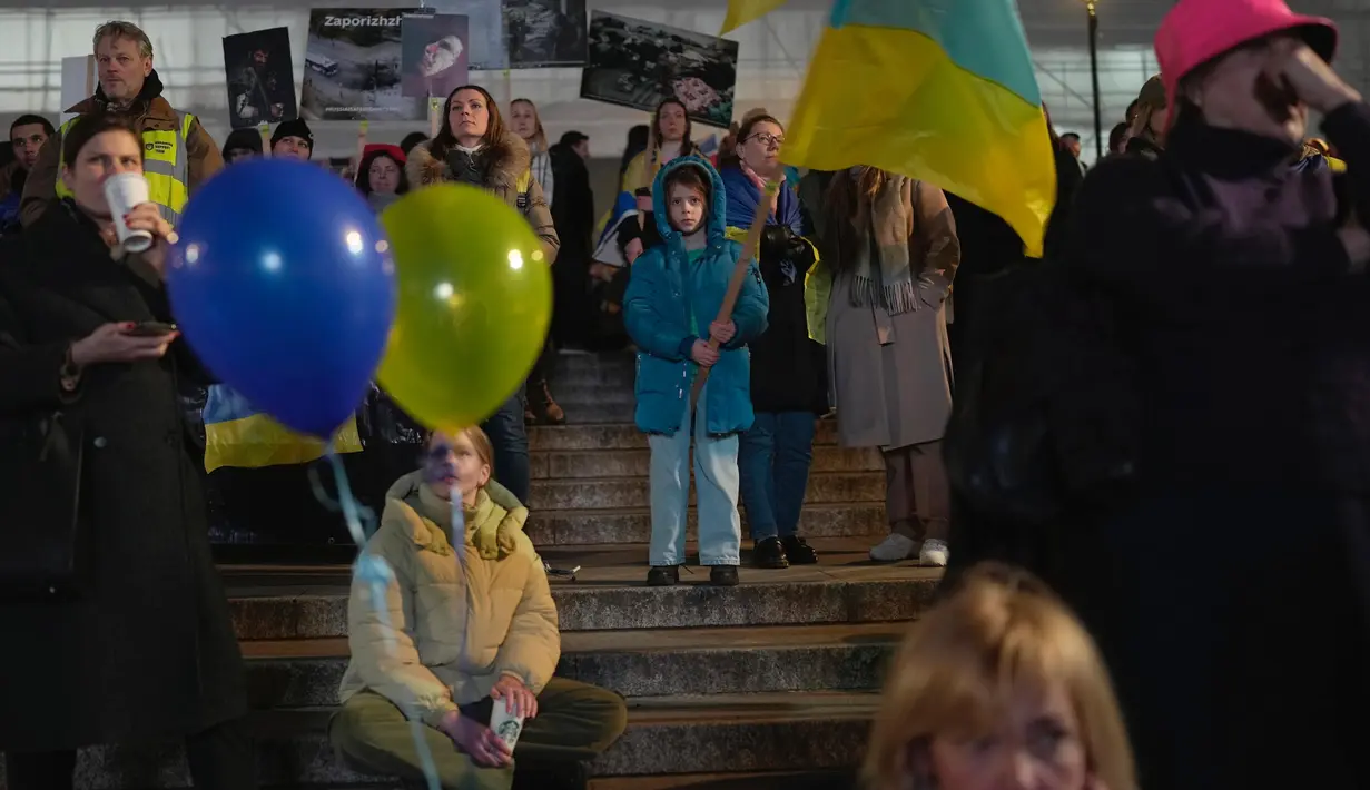 Orang-orang menghadiri sebuah acara di Trafalgar Square yang diselenggarakan oleh Kedutaan Besar Ukraina dan AS, menjelang peringatan satu tahun invasi ke Ukraina, di London, Kamis, 23 Februari 2023. Hasil penelitian yang dirilis oleh German Institute of Economics pada Selasa (21/2/2023) mengungkapkan, perang Ukraina merugikan ekonomi global lebih dari US$ 1,6 triliun atau sekitar Rp24.344 triliun pada tahun 2022. (AP Photo/Kin Cheung)