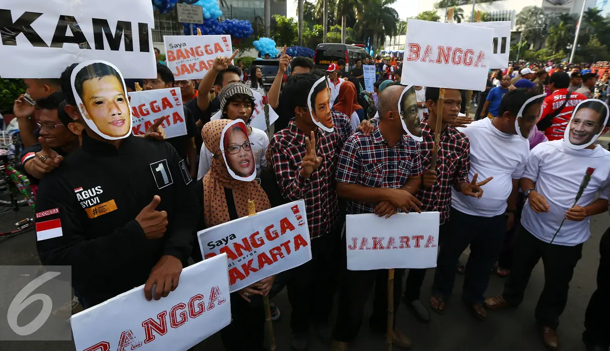 Tiga pasang relawan yang  mengenakan topeng dan atribut tiga paslon Cagub/Cawagub DKI Jakarta membawa papan poster serta mendorong penyelenggara pemilu untuk bekerja secara profesional, jujur dan adil hingga tahapan Pilkada usai.(Liputan6.com/Johan Tallo)