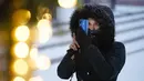 Seorang wanita menggunakan ponselnya untuk memotret dekorasi Natal di Kota Tua di Warsawa, Polandia, pada 10 Desember 2020. Warsawa menyambut salju pertamanya tahun ini pada Kamis (10/12). (Xinhua/Jaap Arriens)
